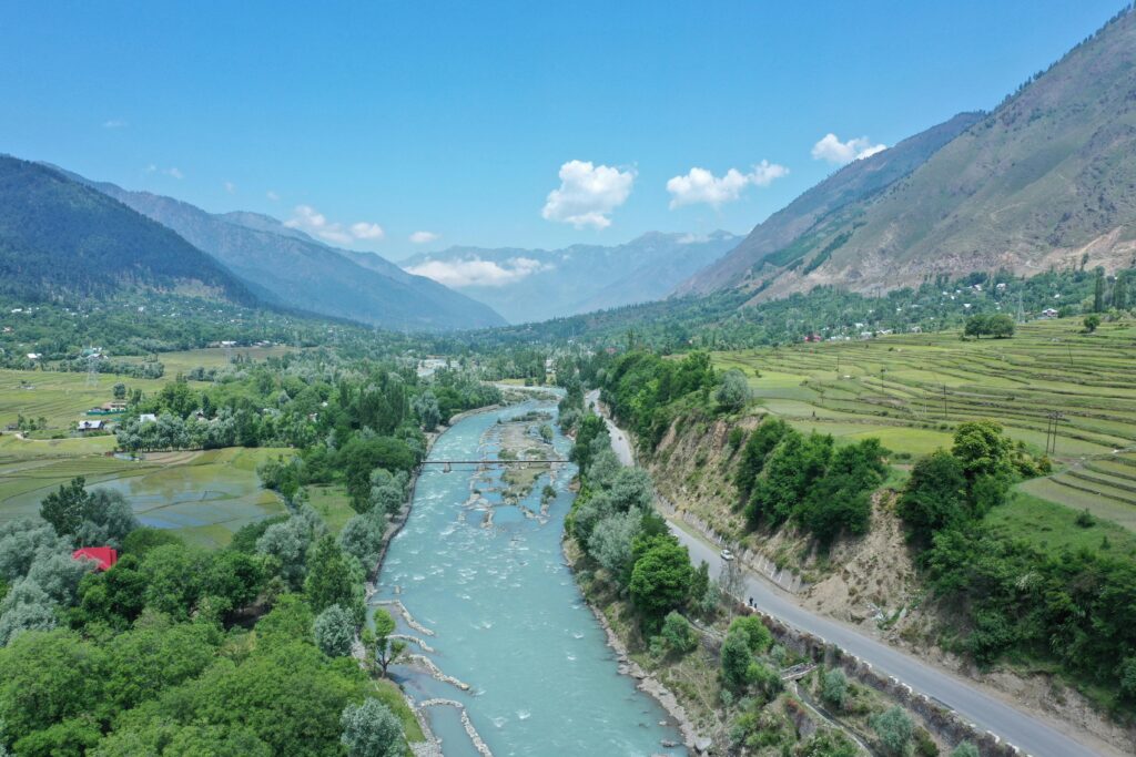 Discover the breathtaking aerial view of a river weaving through the lush Kashmir valley.