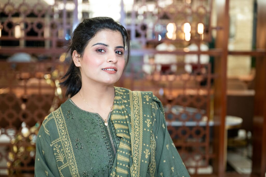 HOME Elegant portrait of a woman in a green traditional dress indoors.