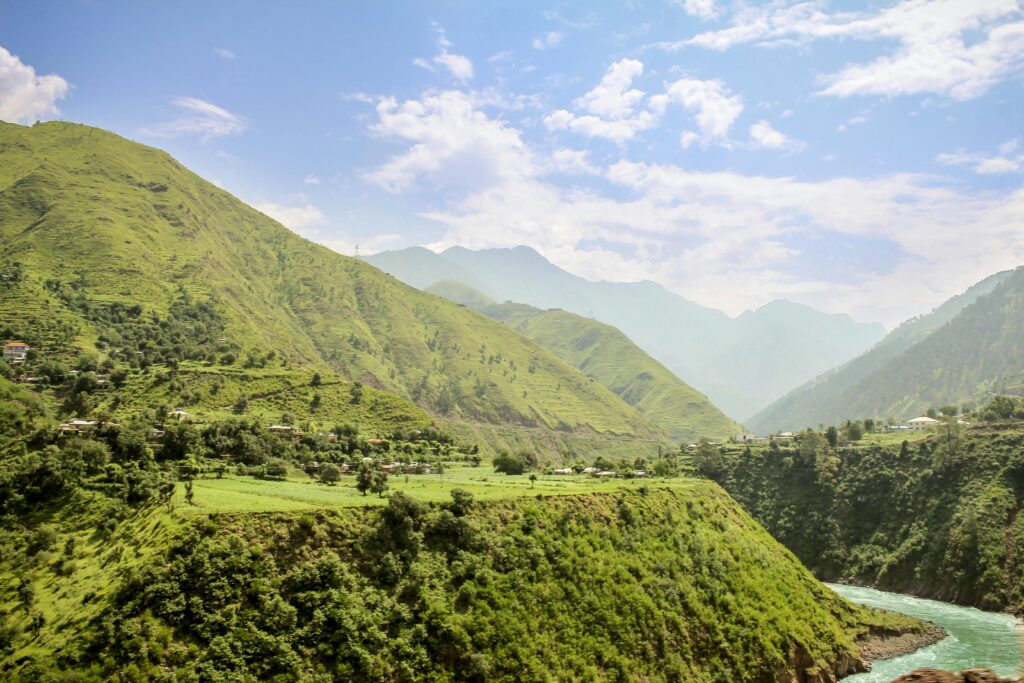 Breathtaking view of lush green mountains and winding river under a clear sky.